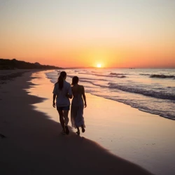 A couple walking at the beach when the sun goes down 